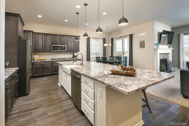 4722 S Netherland St, Centennial, CO 80015 - kitchen with appliances with stainless steel finishes, dark brown cabinetry, a kitchen bar, plenty of natural light, and recessed lighting