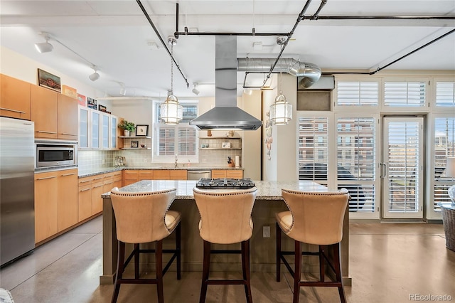 kitchen with hanging light fixtures, sink, light brown cabinetry, tasteful backsplash, and stainless steel appliances