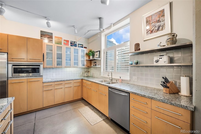 kitchen with light stone countertops, sink, stainless steel appliances, backsplash, and light brown cabinetry