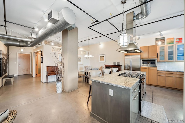 kitchen featuring a center island, hanging light fixtures, built in appliances, decorative backsplash, and light stone counters