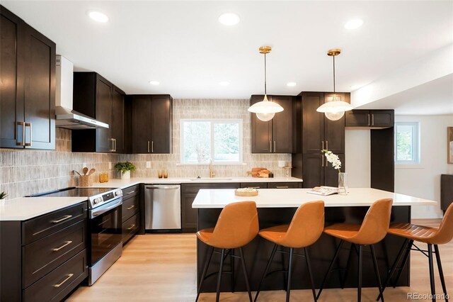 6325 W Portland Pl, Littleton, CO 80128 - kitchen featuring stainless steel appliances, a sink, wall chimney range hood, healthy amount of natural light, and recessed lighting