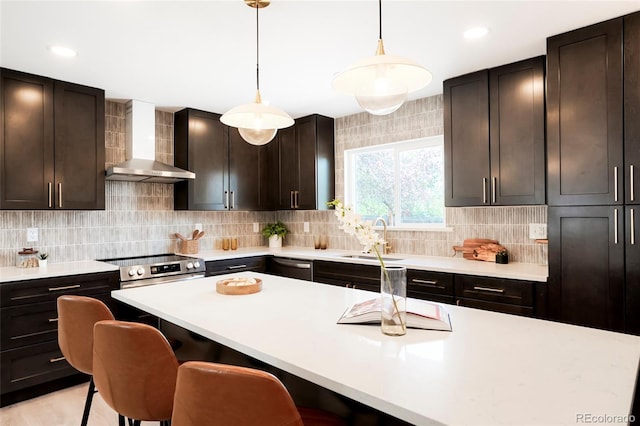 6325 W Portland Pl, Littleton, CO 80128 - kitchen featuring wall chimney exhaust hood, a sink, light countertops, a kitchen breakfast bar, and tasteful backsplash