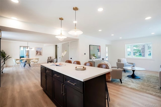 6325 W Portland Pl, Littleton, CO 80128 - kitchen featuring a breakfast bar area, light wood-style floors, a kitchen island, light countertops, and hanging light fixtures