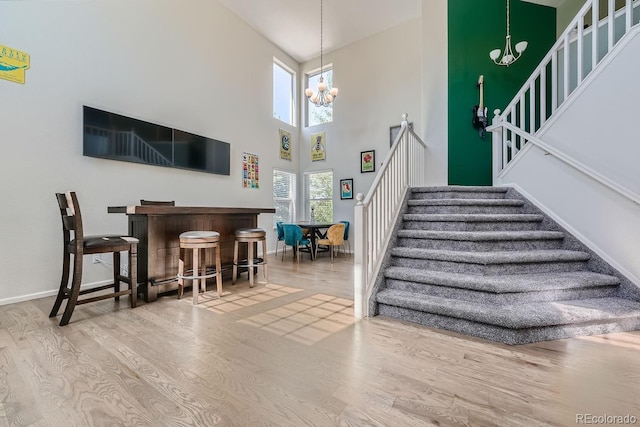 stairs featuring a towering ceiling, hardwood / wood-style flooring, and an inviting chandelier