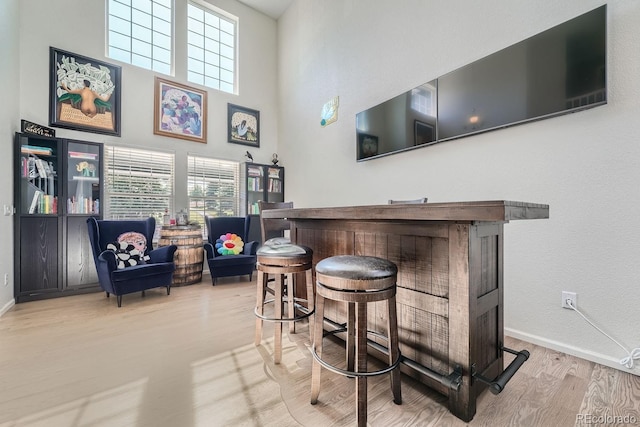 bar featuring light hardwood / wood-style flooring and a towering ceiling