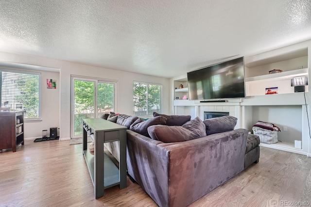 living room featuring a textured ceiling, light wood-type flooring, and a fireplace