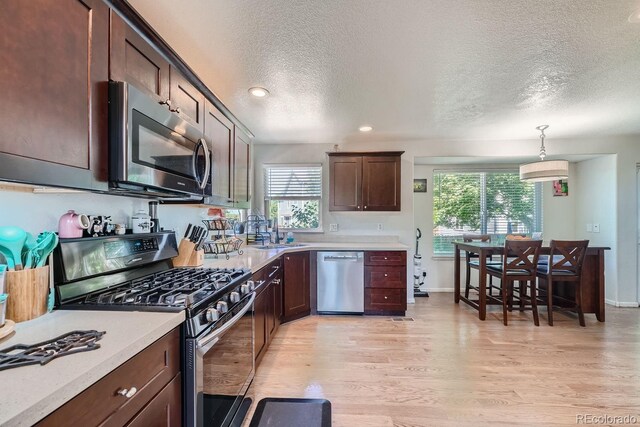 kitchen featuring appliances with stainless steel finishes, a textured ceiling, decorative light fixtures, and plenty of natural light