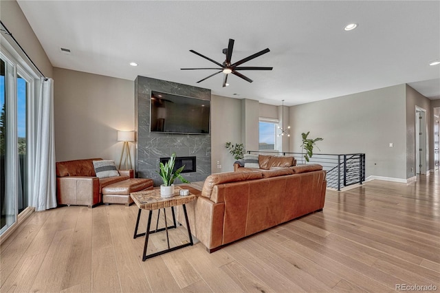 living area with light wood finished floors, visible vents, a fireplace, and a ceiling fan