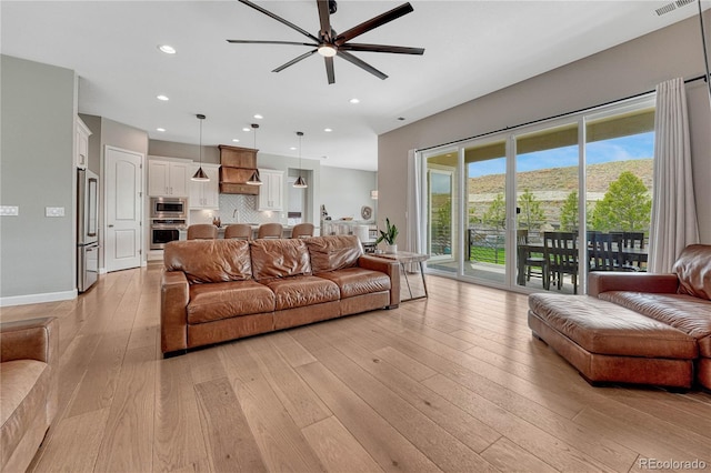 living area featuring light wood-style flooring, a ceiling fan, and recessed lighting