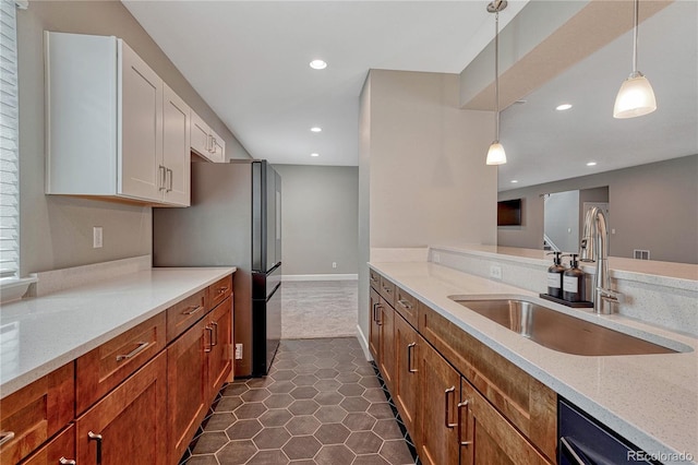 kitchen with decorative light fixtures, light stone counters, a sink, white cabinetry, and dishwashing machine