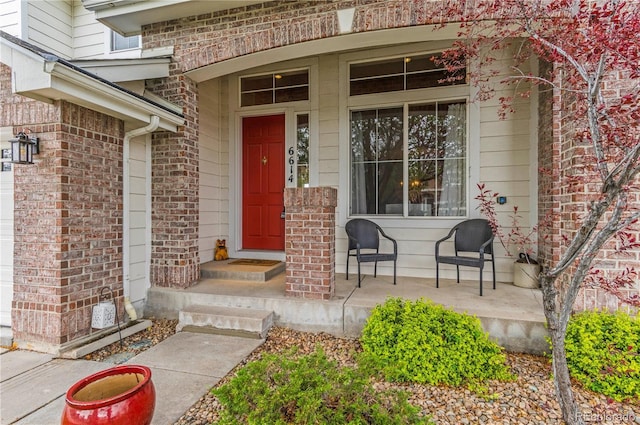 property entrance featuring a porch and brick siding
