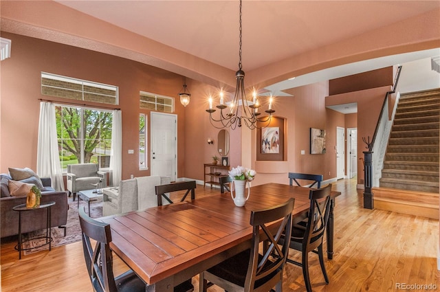 dining space featuring light wood finished floors, stairs, and a chandelier