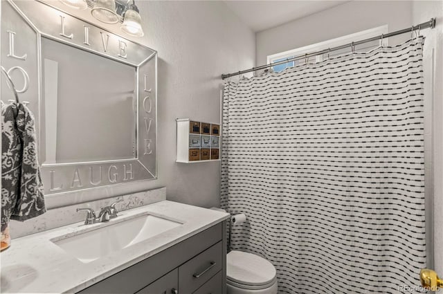 full bath featuring toilet, vanity, a shower with shower curtain, and a textured wall