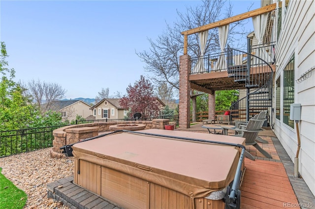 wooden terrace with a hot tub, stairway, and fence