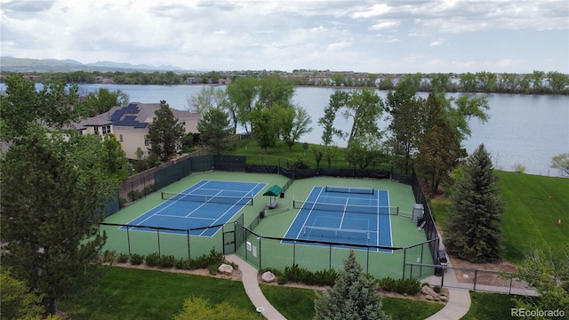 view of tennis court featuring fence and a water view