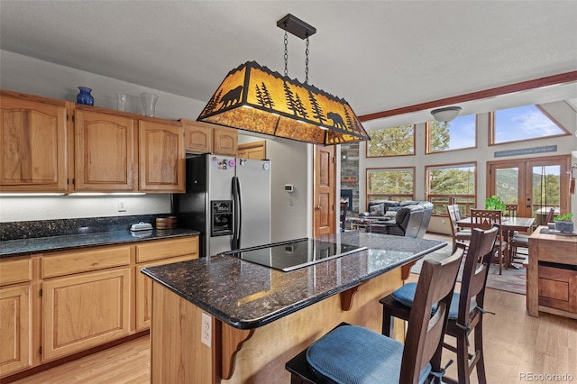 12191 Tecumseh Trl, Conifer, CO 80433 - kitchen with stainless steel fridge, black electric stovetop, light wood-type flooring, and a kitchen bar