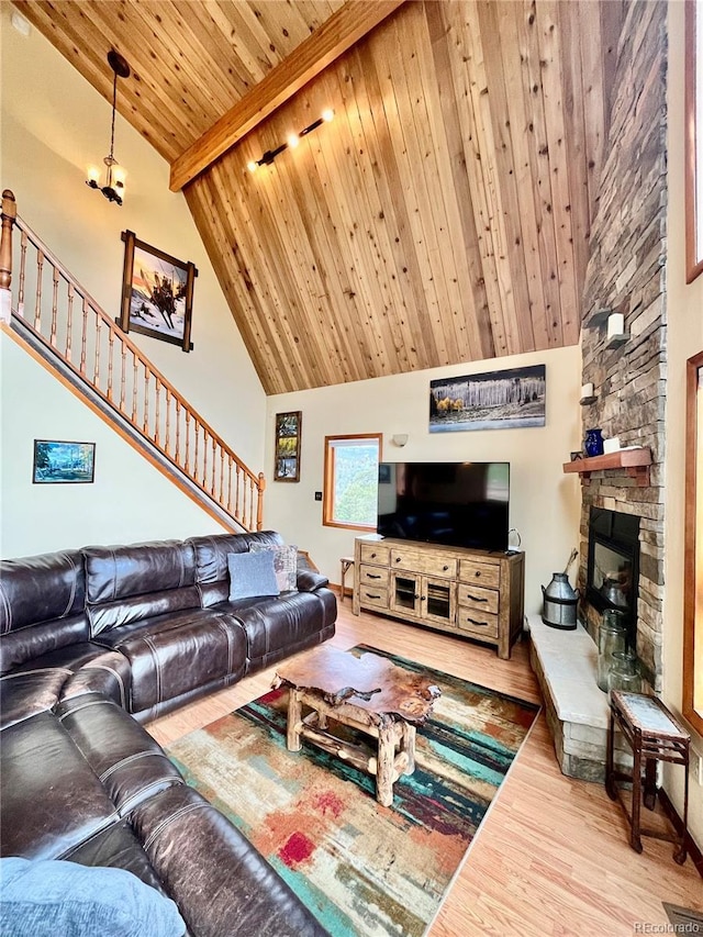 12191 Tecumseh Trl, Conifer, CO 80433 - living area featuring wood finished floors, wood ceiling with exposed beams, a stone fireplace, high vaulted ceiling, and stairway