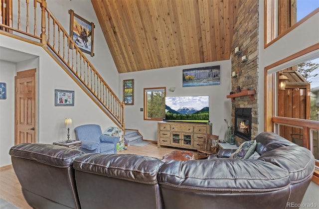 12191 Tecumseh Trl, Conifer, CO 80433 - living area featuring high vaulted ceiling, stairway, wood finished floors, a stone fireplace, and baseboards