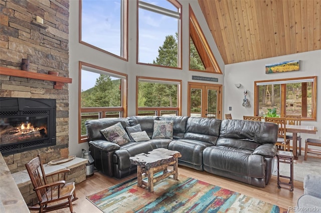 12191 Tecumseh Trl, Conifer, CO 80433 - living area with high vaulted ceiling, light wood-style flooring, a stone fireplace, and french doors