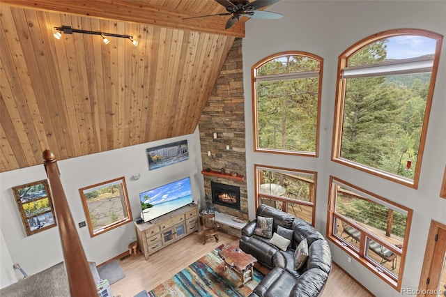 12191 Tecumseh Trl, Conifer, CO 80433 - living area featuring wooden ceiling with exposed beams, high vaulted ceiling, a ceiling fan, a stone fireplace, and wood finished floors