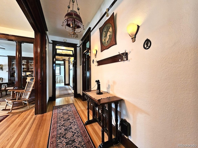243 Park Ave, Salida, CO 81201 - entryway with light wood finished floors, a chandelier, a textured wall, and decorative columns