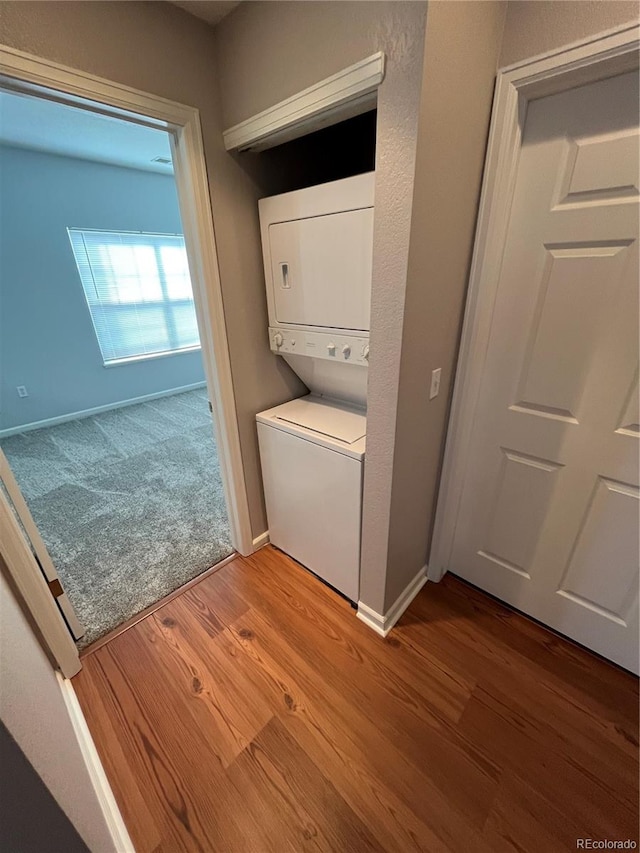 clothes washing area featuring stacked washer / dryer and wood-type flooring