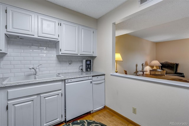 12565 Sheridan Blvd Unit 105, Broomfield, CO 80020 - kitchen with white dishwasher, a sink, light wood finished floors, light countertops, and decorative backsplash