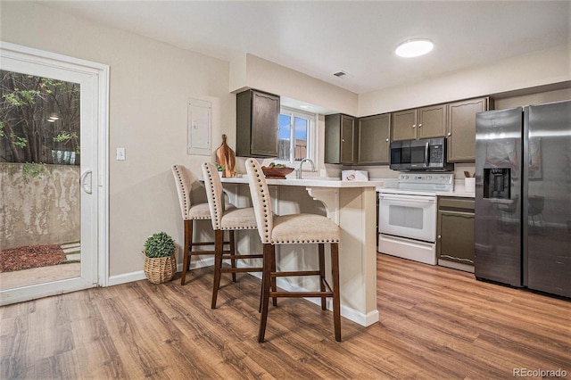 5573 S Lowell Blvd, Littleton, CO 80123 - kitchen featuring appliances with stainless steel finishes, a kitchen bar, light countertops, light wood finished floors, and a peninsula