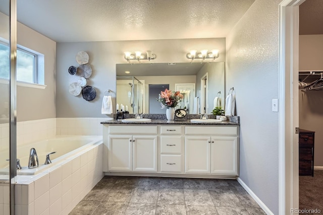 8695 Torrey St, Arvada, CO 80007 - full bath featuring a stall shower, a garden tub, double vanity, a spacious closet, and a textured ceiling
