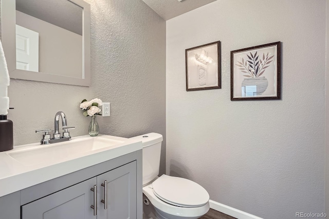 8695 Torrey St, Arvada, CO 80007 - bathroom with a textured wall, vanity, toilet, wood finished floors, and baseboards