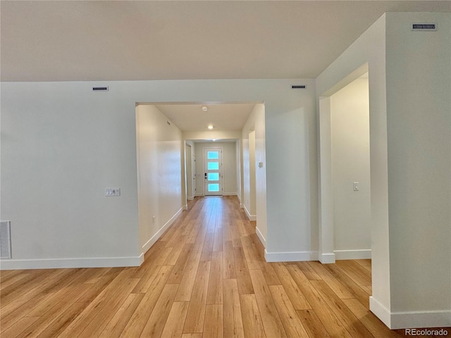 hallway featuring baseboards, visible vents, and light wood-style floors