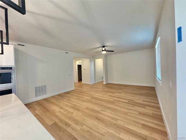 spare room with light wood-style floors, visible vents, baseboards, and a ceiling fan