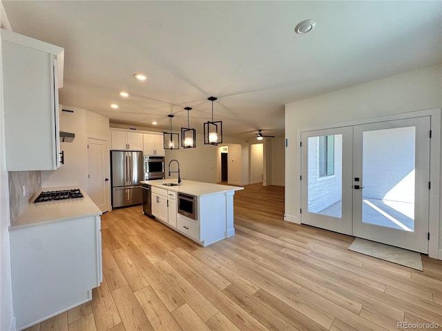 kitchen featuring light wood-style flooring, stainless steel appliances, a sink, white cabinets, and light countertops