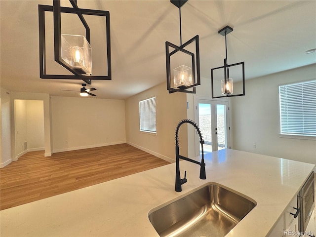 kitchen featuring french doors, decorative light fixtures, open floor plan, a sink, and wood finished floors