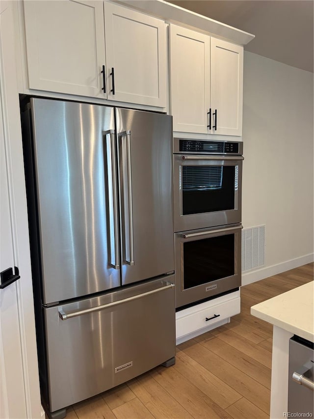 kitchen featuring appliances with stainless steel finishes, visible vents, light wood finished floors, and white cabinetry