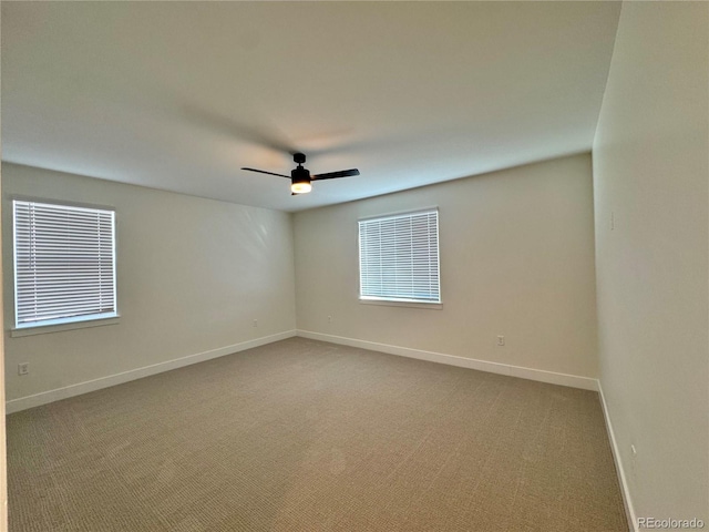 carpeted spare room featuring a ceiling fan and baseboards