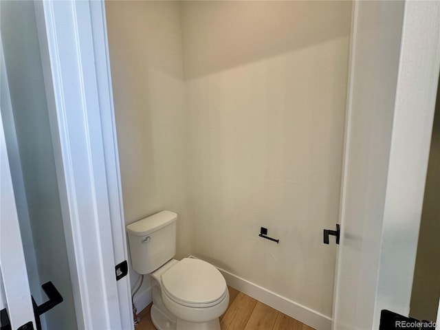 bathroom with baseboards, toilet, and wood finished floors