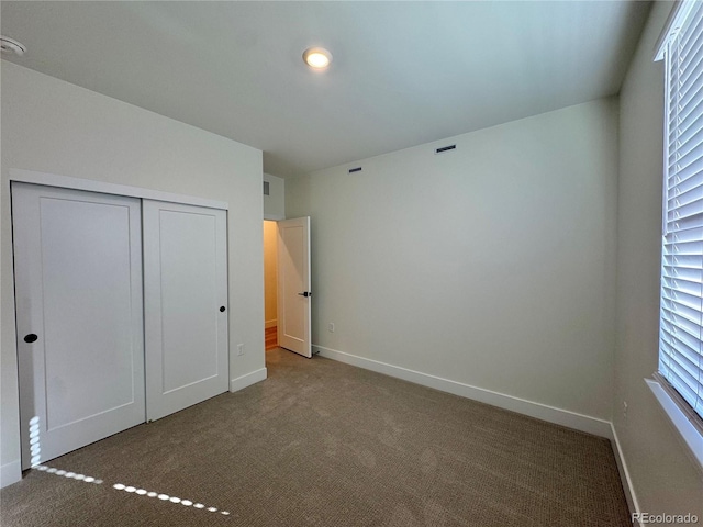 unfurnished bedroom with a closet, carpet flooring, visible vents, and baseboards