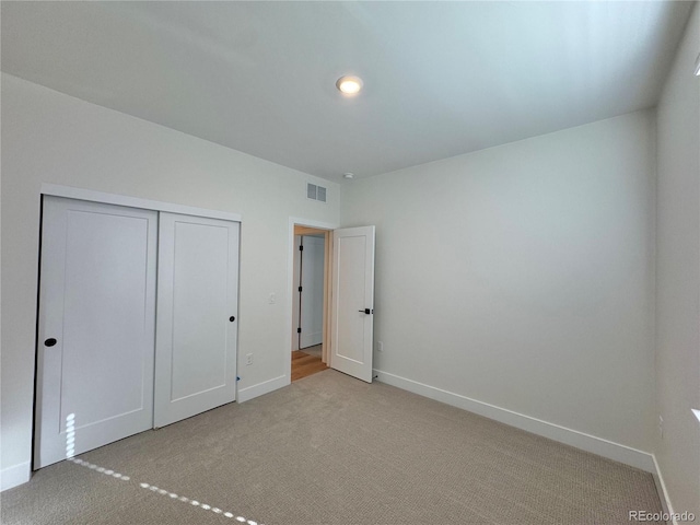 unfurnished bedroom featuring carpet, a closet, visible vents, and baseboards