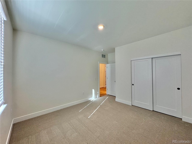 unfurnished bedroom featuring a closet, baseboards, visible vents, and carpet flooring