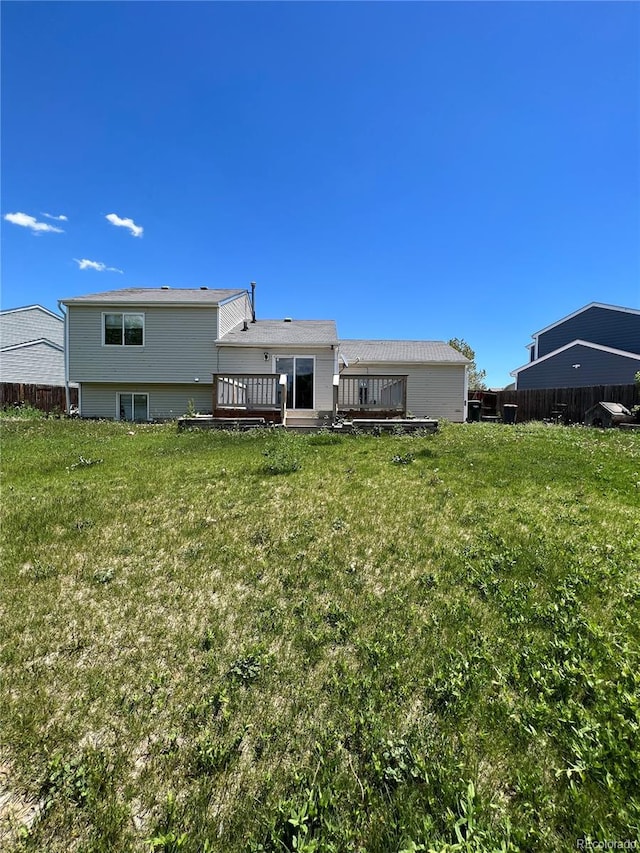 back of property featuring a wooden deck and a yard