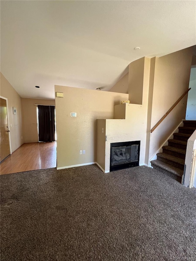 unfurnished living room featuring carpet flooring and vaulted ceiling