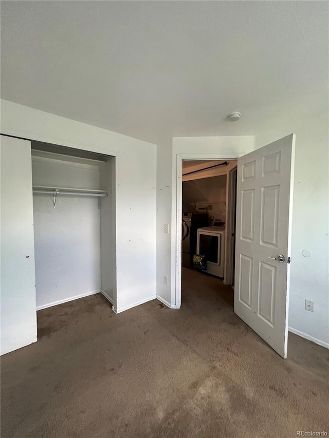 unfurnished bedroom featuring a closet, dark carpet, and independent washer and dryer