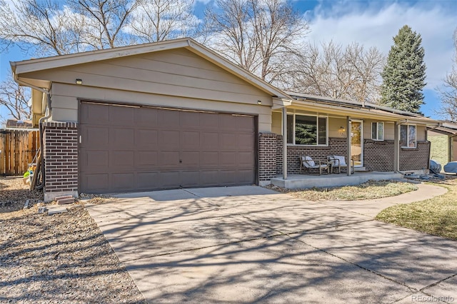 ranch-style house with a porch, fence, concrete driveway, a garage, and brick siding