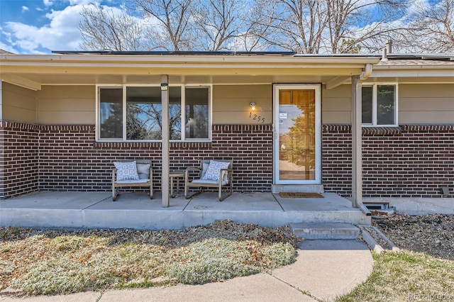 doorway to property with covered porch, brick siding, and crawl space