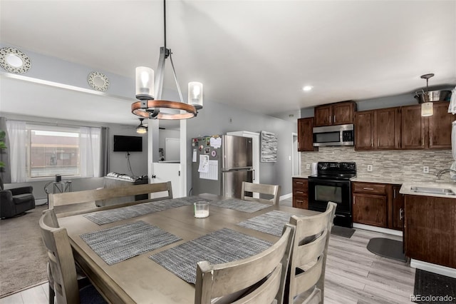 dining area with light wood-type flooring, an inviting chandelier, and baseboards