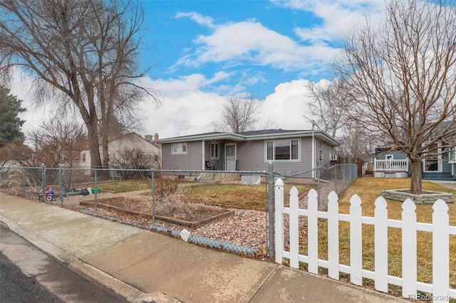 ranch-style home featuring driveway, a front lawn, and a fenced front yard