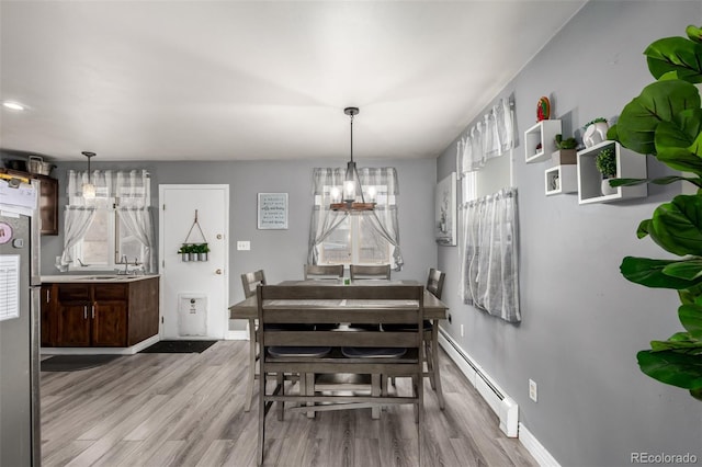 117 6th St, Frederick, CO 80530 - dining room with a baseboard heating unit, a chandelier, light wood-style floors, and baseboards