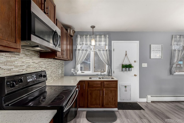 117 6th St, Frederick, CO 80530 - kitchen featuring electric range, stainless steel microwave, a sink, a baseboard heating unit, and light wood-style flooring