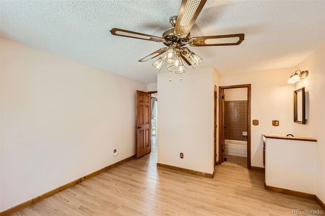 unfurnished bedroom with ceiling fan, ensuite bathroom, a textured ceiling, and light hardwood / wood-style flooring